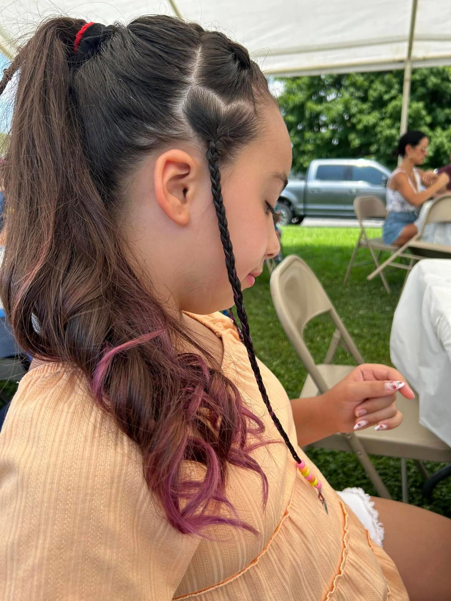 Young guest with sleek braided ponytail and rose-tipped curls styled by Sandy